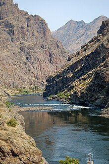 View down a river entering a rocky canyon framed by high cliffs