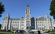 A palace-like building with the flag of Quebec weaving from its central spire