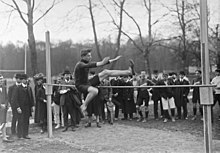 Photographie en noir et blanc d'un homme sautant au-dessus d'une barre.