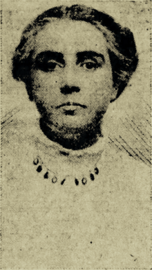 B&W portrait photo of a woman with her hair in an up-do, wearing a pale blouse and necklace.