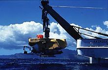 深海探査艇パイシーズ5号、母船船尾からクレーンで吊り下げられ、海面に降ろされているところ。
