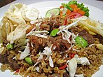 Nasi Goreng, a classic Indonesian fried rice dish, cooked with vegetables, meat, and bumbu (seasoning).