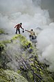 30. Hagyományos kénbányászat az Ijen vulkánnál (Kelet-Jáva, Indonézia). A kép a bányászok veszélyes és nehéz munkakörülményeit mutatja, beleértve a mérgező füstöt és a zuhanásveszélyt, valamint a védőfelszerelés hiányát. A csövek, amelyeken állnak, a kéngőzök elvezetésére és kondenzálására szolgálnak, ami (legalábbis viszonylag) megkönnyíti a termelést (javítás)/(csere)