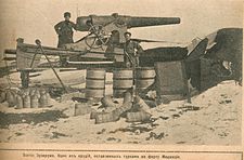 soldier standing in front of a 15 cm caliber gun