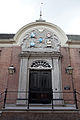 The heraldic shields above the doorway are "Dr. C. van Dam van Aerden", "Dr. M. de Villaneuve", "Mevr. M. van Aerden", "Paulus Drooglever", and "Huibert de Bie".