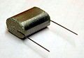 Enrolamento achatado de um capacitor de filme "nu" antes do encapsulamento, com uma visão de camadas colaterais de contato de metal ("schoopage") e terminais conectados