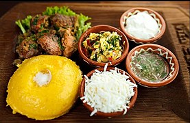 Mămăligă served with salad, cheese, and meat in Moldova