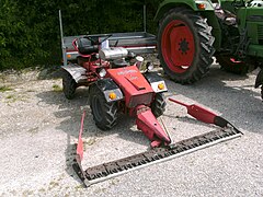 Faucheuse frontale sur un petit tracteur articulé Bucher (ensemble très maniable apprécié en montagne).