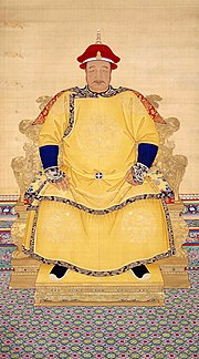 Chân dung toàn mặt of a corpulent man with a thin mustachio đội một chiếc mũ đỏ và khoác bào phục màu vàng có hình rồng, ngồi trên ngai vàng.