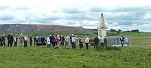 personnes groupées autour d’un monument dans la campagne