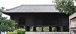 Dark wooden building with raised floor on poles.