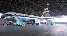 Vue d'un avion biréacteur de Delta Air Lines dans un hangar avec des escaliers installés près de la porte avant.