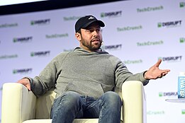 Scooter Braun seated in a chair onstage at a conference