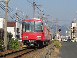 両側を道路に挟まれた専用軌道を走る普通列車