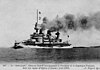 A black and white photo of a steaming battleship