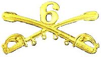 A computer generated reproduction of the insignia of the Union Army 6th Regiment cavalry branch. The insignia is displayed in gold and consists of two sheafed swords crossing over each other at a 45 degree angle pointing upwards with a Roman numeral 6