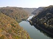 A view of a river winding through a narrow valley, flanked by forested mountain ridges.