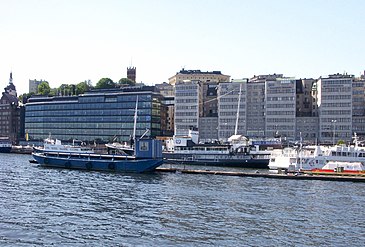 Fotografiet till vänster togs 1925 av Gustaf W. Cronquist på en autochromplåt och visar Stadsgårdens bebyggelse närmast Slussen. Här skedde stora förändringar i stadsbilden tills nästa bild som togs år 2010. Det enda huset som känns igen är det så kallade Sjömansinstitutets hus från 1914 som skymtar längs ut till vänster. Resten av bebyggelsen utgörs av de båda KF-husen. Det äldre är en ombyggnad från början av 1930-talet av det stora röda tegelhuset till höger som byggdes för Kooperativa förbundet mellan 1909 och 1912. Det nyare, även kallat "Glashuset", uppfördes på 1970-talet på platsen för bland annat Drottsgården.