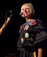 A picture of a blonde haired woman, smiling while performing