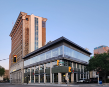 A squat, modern building of steel, glass, and concrete pillars is shown attached to the back of a taller and much older building clad in brick and stonework. The nearer building has signage, "Paterson GlobalFoods Institute"