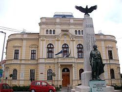 Városháza, előtérben az I. és II. világháborús hősi emlékmű.