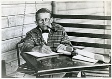 Myers smokes a pipe and writes with a pen and paper.