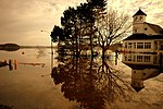 A flooding river has inundated roads, trees, and an elegant building.