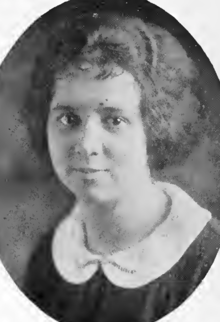 A yearbook photo of a young white woman with short wavy hair; she is wearing a round white collar on a dark dress