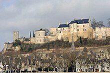 Photographie d'un château aux murs blancs au sommet d'une colline avec une ville en contrebas