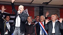 Photographie d'Alan Stivell au micro sur scène devant les élus bretons