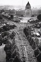 Photo aérienne noir et blanc d'un carrefour de deux avenues bordées par des arbres, dans lesquelles est rassemblée une foule immense. Le bâtiment de l'assemblée nationale forme l'arrière-plan de l'image.