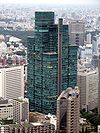 Aerial view of a green, glass high-rise composed of square sections that rise to differing heights