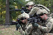 US Army 10th Mountain Division soldiers; (bottom‑left) AN/PEQ-15 attached to an M4 carbine; (bottom‑right) DBAL-A2 attached to M249 SAW.