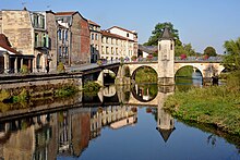 Pont et quai adjacent et leur reflet dans le cours d'eau.