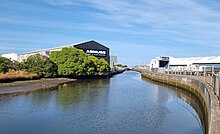 Photo of stream surrounded by industrial buildings.