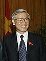 a smiling man with greying black hair, wearing a suit and tie