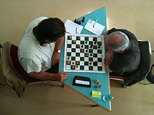 Photographie prise au-dessus de deux joueurs devant un échiquier.