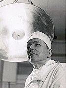 Portrait en contre-plongée d'un chirurgien dans une salle d'opération en noir et blanc.