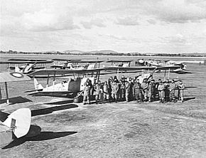 Men in flying suits with single-engined several military biplanes