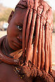 Ein Mädchen der Himba verdeckt mit ihrer Haartracht das Gesicht.