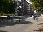 Cykelöverfart (och övergångsställe). Såväl trafik på gatan som på cykelbanan till höger om denna skall här väja för den korsande cykelvägen enligt skyltning och vägmarkeringar). Trafiken på gatan skall dessutom väja för gående på övergångsstället (men detta gäller enligt skyltning och markeringar inte trafikanter på cykelbanan längs gatan).