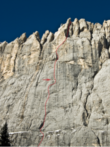 Die steile, mehrere hundert Meter hohe Marmolata-Südwand, der ungefähre Verlauf der Kletterroute "Weg durch den Fisch" ist in rot eingezeichnet. Die Felsnische "Fisch" ist durch einen roten Pfeil gekennzeichnet.