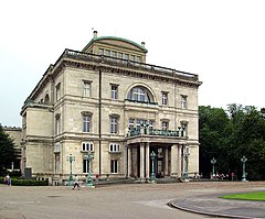 a) značka rodinného podniku Krupp-Konzern, b) Villa Hügel, rodinné sídlo v Essenu