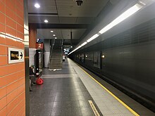 Underground tiled station platform with stairs in the distance heading up towards ground level