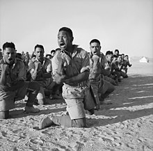 Maori men kneeling, performing the haka