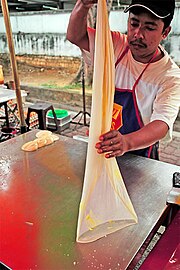 Maleisische roti canai tot een flinterdun vel uitgeslingerd