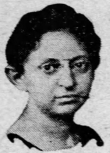 A middle-aged woman with light skin and dark hair, wearing wire-rimmed glasses. Half-tone image from a 1924 newspaper.