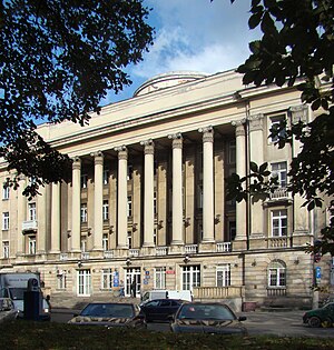 Un bâtiment beige avec des colonnes sur plusieurs étages.