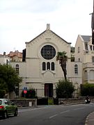 Façade d'un bâtiment ; étoile de David au centre d'une baie vitrée surmontant le portail.