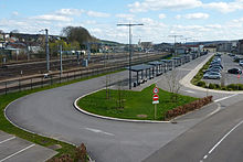 Photographie d'une rue menant à des abribus en ligne le long d'une voie ferrée.